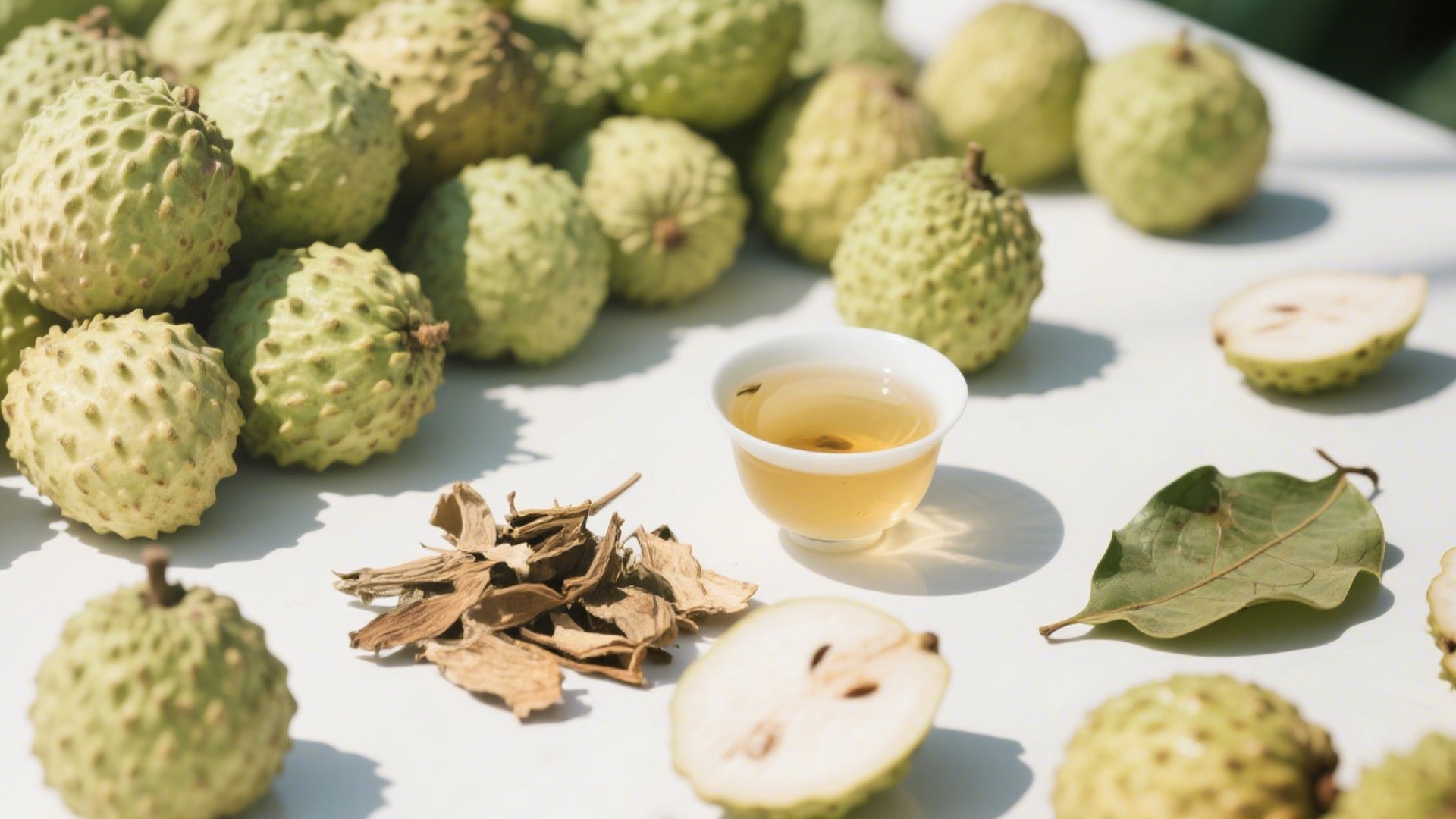 Fresh soursop fruit alongside dried soursop leaf tea leaves and a glass of organic soursop leaf tea, highlighting natural wellness.